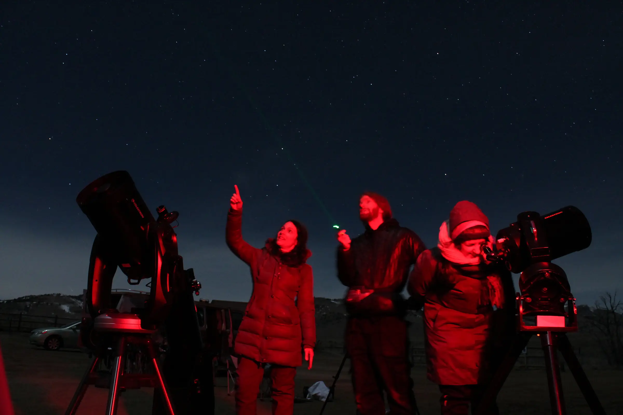 Guests and astronomers observing through large telescopes beneath a starry sky